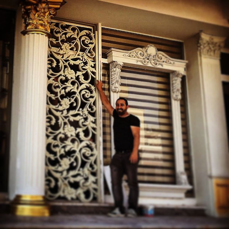 Intrare rezidențială decorată cu panou ornamental din poliuretan, coroană de fereastră și coloane clasice albe.