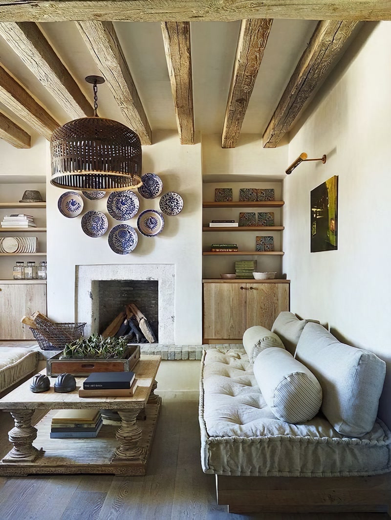 Salon rustic decorat cu grinzi din poliuretan pe tavan, șemineu din piatră și canapea din in natural.