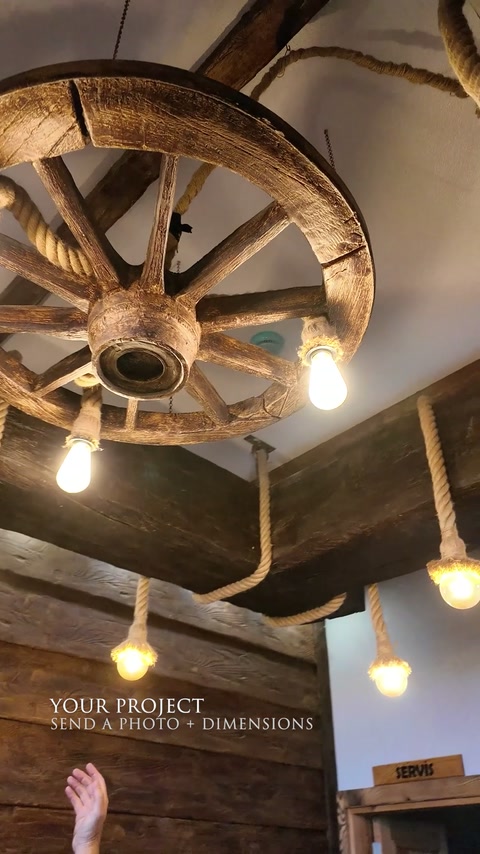 Grinzi rustice, roată decorativă și becuri suspendate amenajează plafonul.