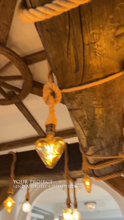 Grindă de plafon cu relief rustic, frânghii și iluminat cald.