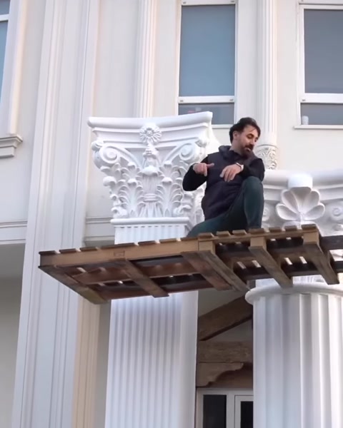 Muncitor așezat pe schelă lângă un capitel finalizat
