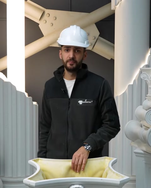 Muncitor cu cască stă lângă o coloană albă din poliuretan.