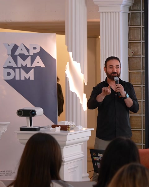 Prezentatorul susține discursul lângă coloane decorative și materiale vizuale.