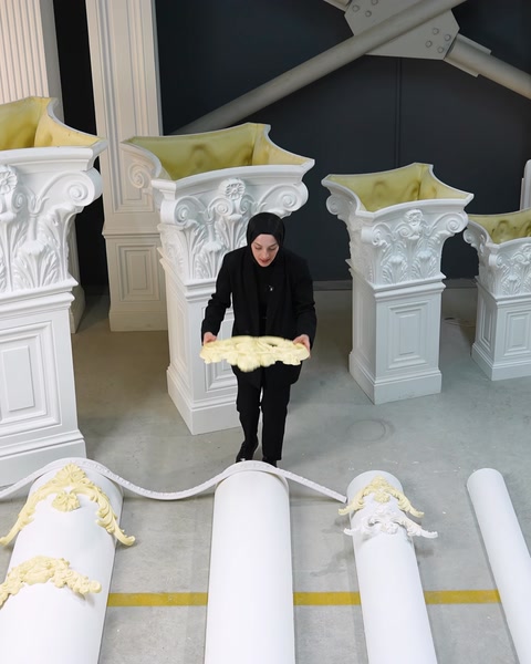 Femeie transportă un profil decorativ flexibil spre coloanele demonstrative din showroom.