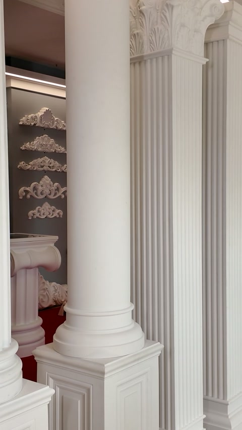 Coloană decorativă albă cu bază profilată și capitel sculptat în expoziție