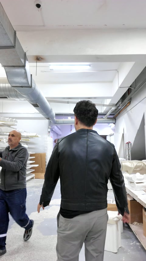 Discuție tehnică în atelier, lângă ancadramente și reliefuri decorative.