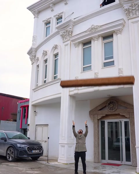 Bărbat sărbătorește lângă clădire, grindă decorativă suspendată în aer