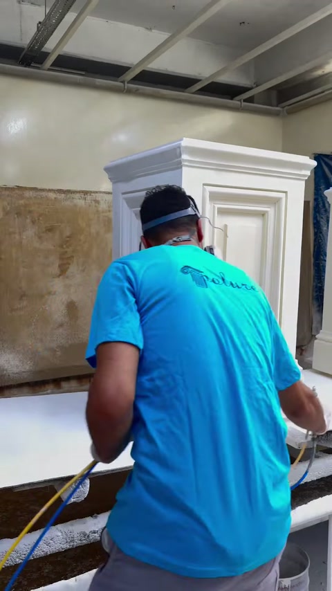 Lucrătorul pulverizează stratul de finisare pe baza decorativă.