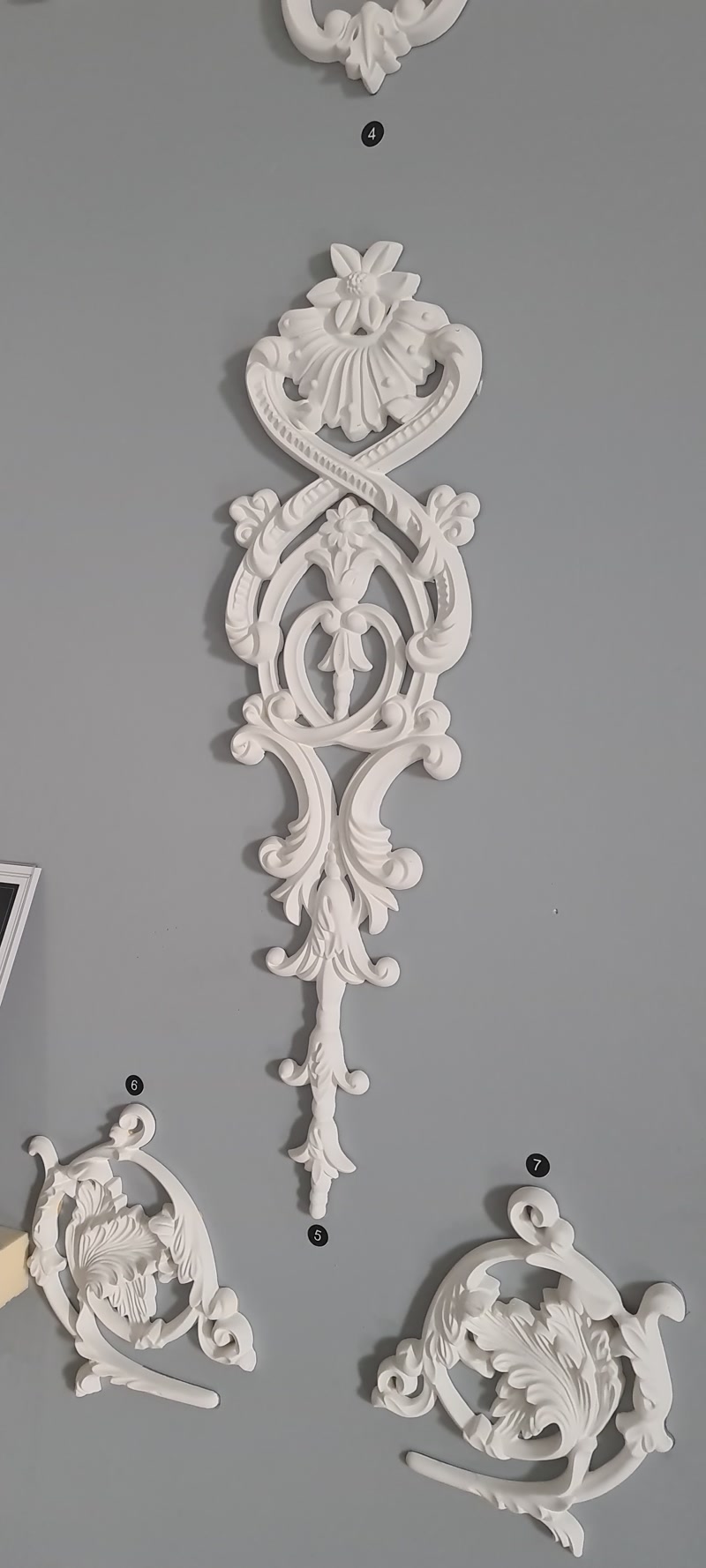 Element Decorativ Din Poliuretan P8055A Pentru Pereți Elementele decorative din poliuretan sunt piese de ornamentație arhitecturală destinate accentuării pereților interiori în stil clasic sau neoclasic. În sufrageria spațioasă a vilei noastre, am dorit să creăm un punct de atracție vizuală pe peretele principal, fără a încărca atmosfera generală. Alegerea modelului P8055A a adus exact nota de eleganță tradițională pe care o căutam pentru serile confortabile petrecute în familie.
Profilul ornamentat din poliuretan are o densitate ridicată de 150-220 kg/m³ (țintă ~160 kg/m³), garantând o durabilitate excelentă la impact și schimbări de mediu. Piesele au o rezistență termică remarcabilă între -100 °C / +80 °C, ceea ce le face potrivite chiar și în apropierea surselor de căldură moderate. Cu un finisaj de suprafață fin, pre-vopsit în alb, elementele decorative au o absorbție de apă sub 1%, ceea ce previne deformările în timp și asigură o aplicare impecabilă a vopselei lavabile pe bază de apă.
Montajul acestor ornamente decorative pe perete s-a realizat extrem de ușor cu ajutorul unui adeziv acrilic special, fără a fi nevoie de intervenții structurale complexe. Copiii și oaspeții noștri admiră mereu detaliile fine ale modelelor sculptate, precum frunzele de acant și rozetele delicate. Aplicarea a 2 straturi de vopsea satinată a uniformizat perfect nuanța ornamentului cu restul peretelui, creând un efect de basorelief integrat direct în tencuială.
Transformarea sufrageriei într-un spațiu primitor și rafinat a schimbat complet dinamica zilnică a căminului nostru. Fiecare ornament din poliuretan adaugă adâncime vizuală și structură, transformând un simplu perete într-un fundal sofisticat pentru momentele speciale în familie. Alegerea elementelor decorative potrivite este secretul pentru a transforma o casă nouă într-un acasă plin de căldură și personalitate.
