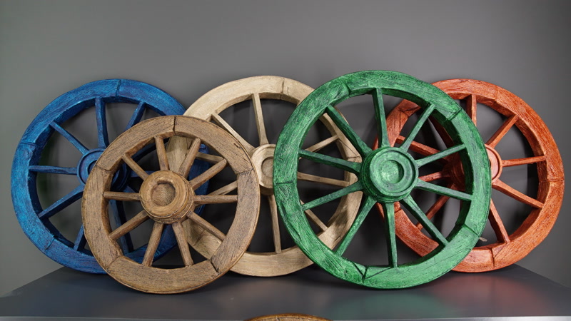 Cinci roți decorative din poliuretan colorate în albastru, verde și maro cu aspect de lemn rustic montate pe perete.