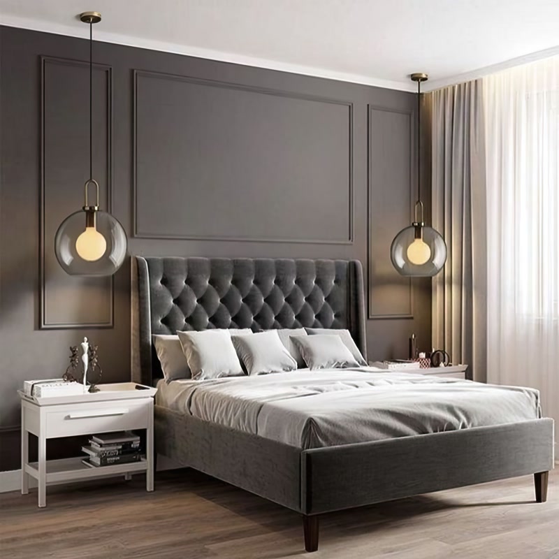 Amenajare Dormitor cu Baghete din Poliuretan Profilul din poliuretan pentru decorarea pereților este un element arhitectural din polimer de înaltă densitate (150-220 kg/m³ (țintă ~160 kg/m³)) folosit pentru crearea casetelor decorative și adăugarea de profunzime spațiilor interioare. În acest dormitor primitor, peretele din spatele patului a fost transformat într-un punct focal relaxant prin aplicarea unor rame dreptunghiulare ample, vopsite într-o nuanță profundă de gri antracit. Atmosfera creată în fiecare seară este una caldă și intimă, ideală pentru deconectarea după o zi lungă de muncă, unde textura catifelată a tăbliei de pat se îmbină perfect cu liniile geometrice ale peretelui.
Compoziția parietală combină profilul principal din poliuretan P85016 cu bagheta secundară P85403, obținându-se un joc subtil de reliefuri și umbre pe suprafața peretelui. Materialul poliuretanic de înaltă calitate prezintă o rezistență termică excelentă între -100 °C / +80 °C și o rată de absorbție a apei de sub 1%, prevenind deformarea în timp sau crăparea la îmbinări. Lipirea profilelor s-a realizat cu un adeziv structural poliuretanic special, fiind necesar un timp de uscare de 24 ore înainte de finisarea îmbinărilor cu hârtie abrazivă de granulație 200 și aplicarea vopselei lavabile.
Privit din perspectiva vieții de zi cu zi, acest dormitor oferă acel sentiment confortabil de acasă, unde lumina caldă emisă de pendulele cu abajur din sticlă tăiată pune în valoare detaliile volumetrice ale baghetelor. Nuanțele închise ale peretelui creează un efect de protecție și calm, în timp ce noptiera albă din lateral oferă o notă de prospețime și un contrast vizual plăcut. Casetele mari formate din profile din poliuretan oferă structură camerei fără a o încărca, permițând textilelor moi și pernelor confortabile să preia rolul principal în crearea stării de bine.
Alegerea decorului cu profile din poliuretan P85016 și P85403 reprezintă o soluție durabilă și ușor de întreținut pentru orice familie care dorește să îmbunătățească estetica dormitorului fără lucrări complexe de zidărie. Suprafața amorsată din fabrică permite aplicarea a 2 straturi de vopsea lavabilă pe bază de apă, asigurând o curățare facilă prin simpla ștergere cu o lavetă umedă. Datorită structurii solide și montajului curat, acest tip de decor parietal își menține aspectul impecabil ani la rând, transformând dormitorul într-un spațiu liniștit și primitor pentru întreaga familie.