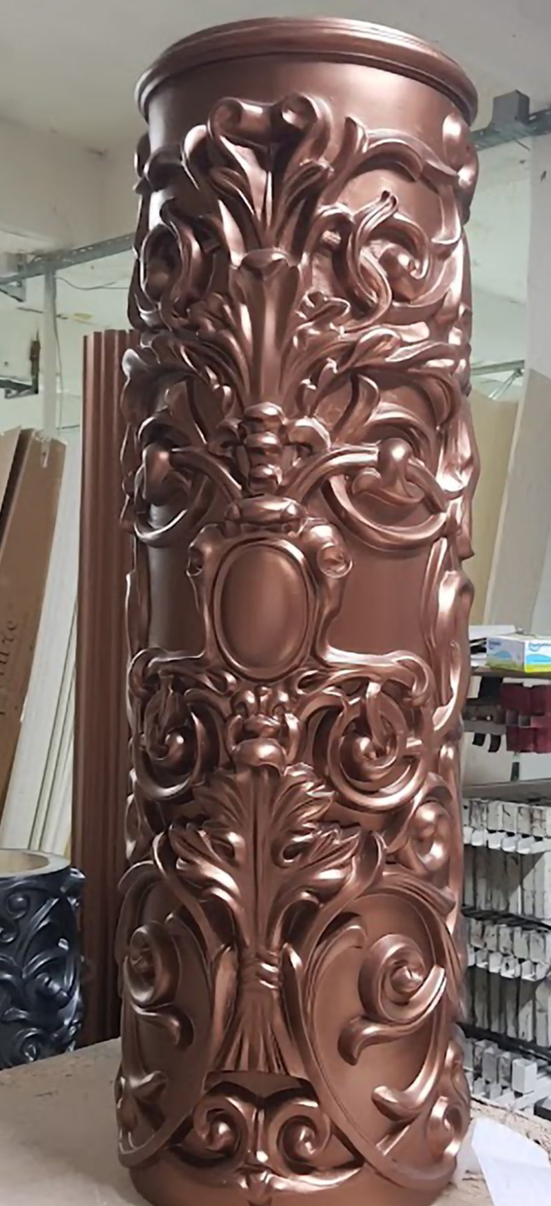 Coloană decorativă din poliuretan model P5540 cu motive florale baroce și finisaj metalic bronz în atelier.